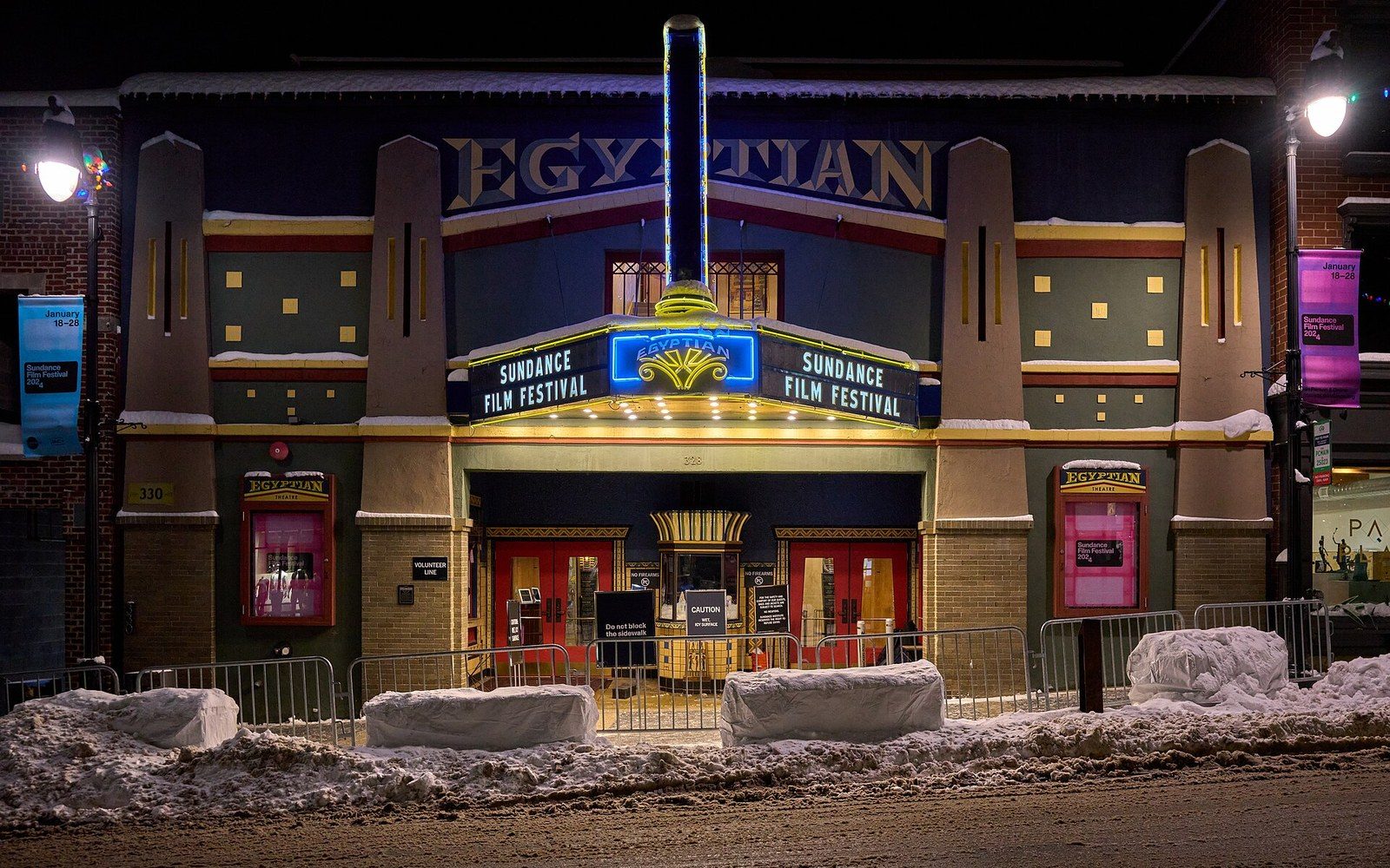 The Egyptian Theatre lit up at night with Sundance Film Festival signage, snow piled outside