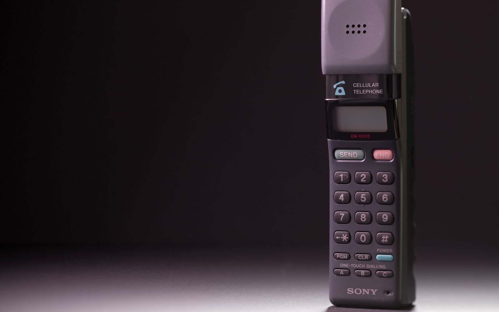 A vintage Sony cellular telephone with keypad standing upright against a dark background