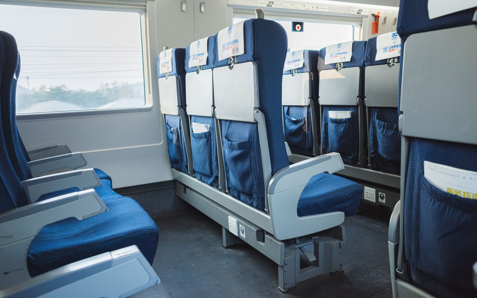 Rows of blue upholstered seats with headrest covers inside a train carriage